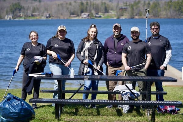 EDM team standing in front of a picnic bench at a lake